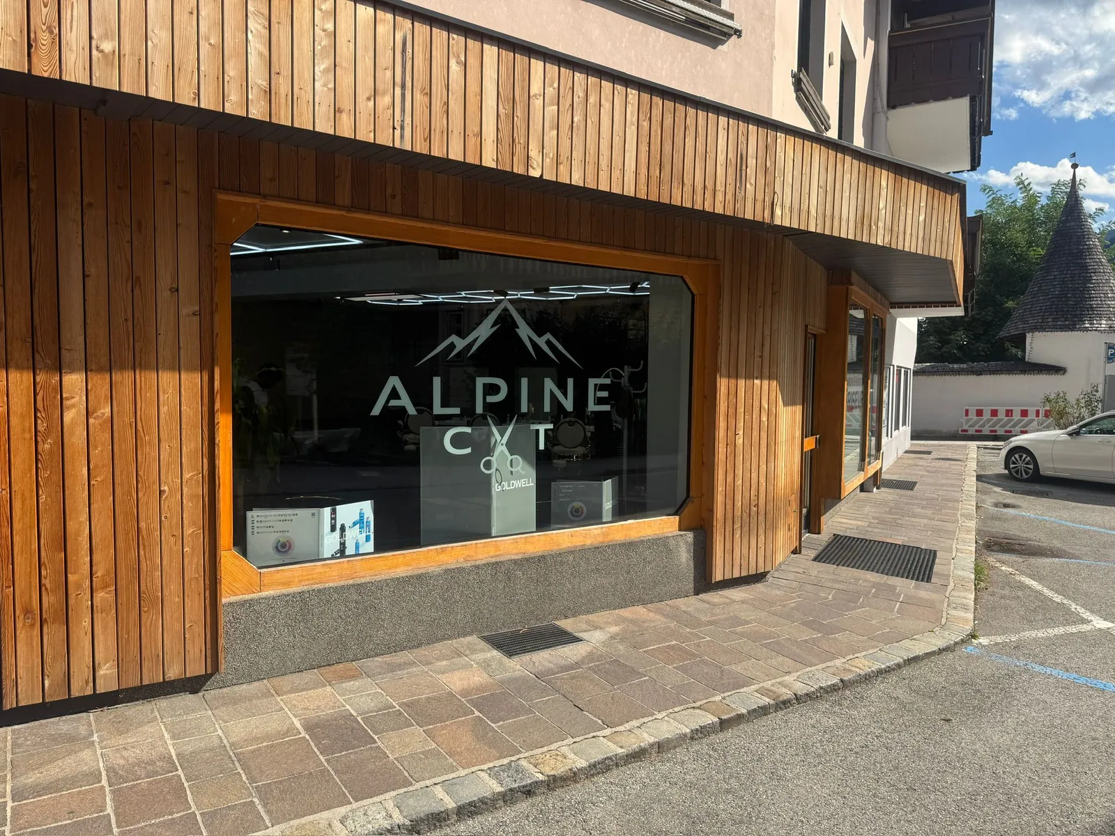 Der Salon von außen: Holzfassade am Dorf-Platz, das Alpine-Cut-Logo im Schaufenster.