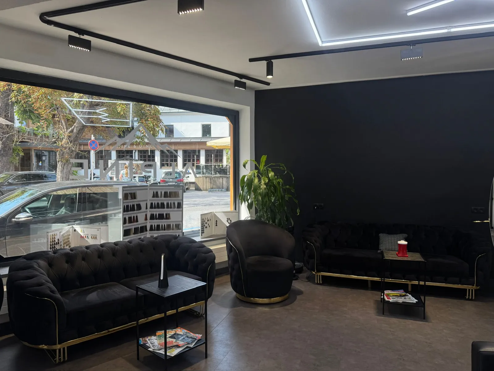 Wartebereich mit schwarzen Chesterfield-Sofas und Messingfüßen am Schaufenster.